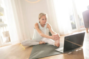Woman 40+ practices yoga at home with notebook. Online yoga class. Woman 40+ practices yoga at home with notebook. Online yoga class.